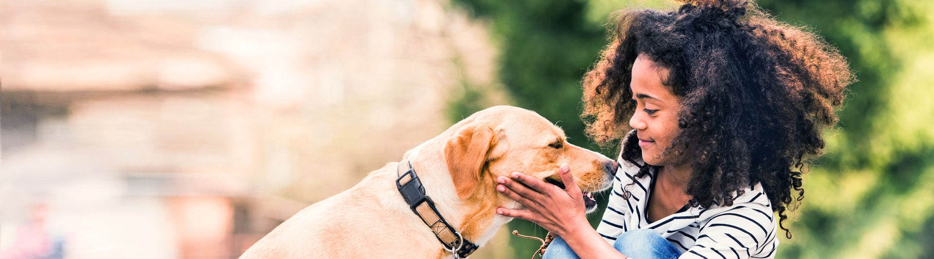 African american girl outdoors on skateboard with her dog.