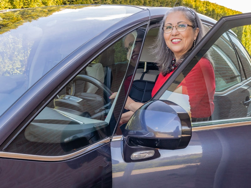 Happy older woman getting into her car